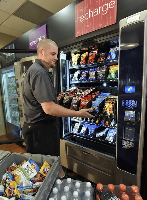 Technician restocking snacks in a well-lit breakroom